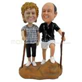 The couple are leaning on a stick in mountaineering custom bobbleheads