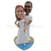 Custom couple bobbleheads stand on the beach