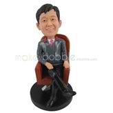 The man sits on a wooden chair custom bobbleheads